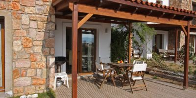 Holiday vacation villa exterior view with a wooden table and chair set laid up for an al-fresco snack